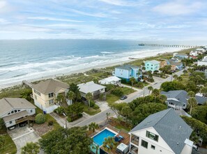 A coastal residential area with houses, a beach, and a pier.