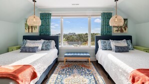 Une chambre avec deux lits, une grande fenêtre, une vue sur la ville et un tapis à motifs.