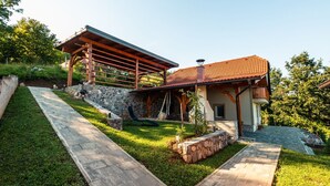 Una casa moderna con fachada de piedra, una pérgola de madera y un techo de tejas.