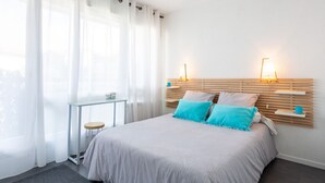 A bedroom with a bed, bedside tables, a nightstand, and a window with sheer curtains. - mille sabords by Interhome (Capbreton)