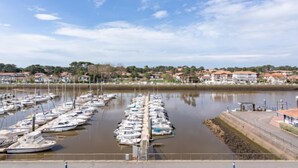 A marina with numerous boats docked, a calm water body, and a residential area in the background. - mille sabords by Interhome (Capbreton)