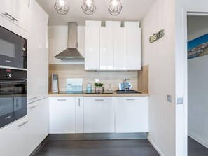 A modern kitchen with white cabinets, a Bosch oven, a coffee machine, and a sink. - mille sabords by Interhome (Capbreton)