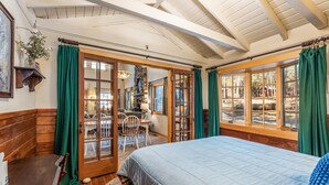 Um quarto aconchegante com cama, paredes de madeira, área de refeições e janelas amplas.