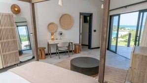 A bedroom with a bed, desk, and a view of the ocean. - Sunset Vista Suite – Panoramic Ocean Retreat at Tamarind Hills, Antigua (Ffryes beach)