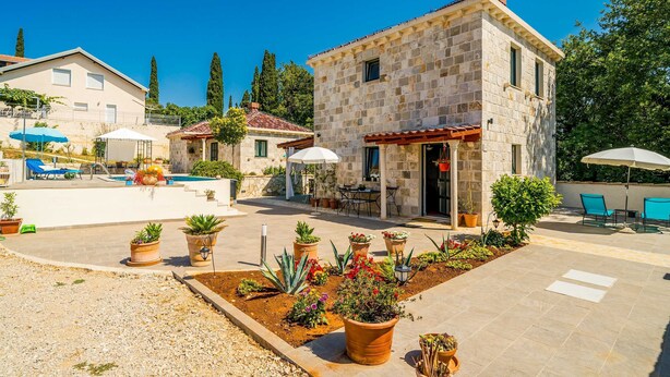A stone building with a pool, outdoor seating, and potted plants. - Dubrovnik Chalets (Konavle)