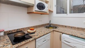 Een kleine keuken met een magnetron, fornuis en spoelbak.