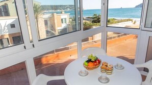 Een balkon met een gedekte tafel voor thee, met uitzicht op de kust, gebouwen en de zee.