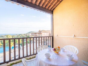 Enjoy a refreshing view of the pool from this balcony, complete with a dining area and comfortable seating.