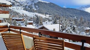 Un balcó de fusta amb vista a un paisatge de muntanya cobert de neu i diverses cabanes de fusta.