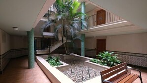 A spacious atrium with a central water feature, a wooden bench, and a staircase leading to an upper level. - Golden Beach by Interhome (St Carles de la Ràpita)