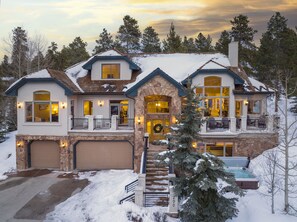 A large, two-story house with a stone facade, multiple windows, and a front porch with outdoor seating.