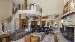 Amplia sala de estar con una escalera curva, una chimenea y un ventanal con vistas al exterior.