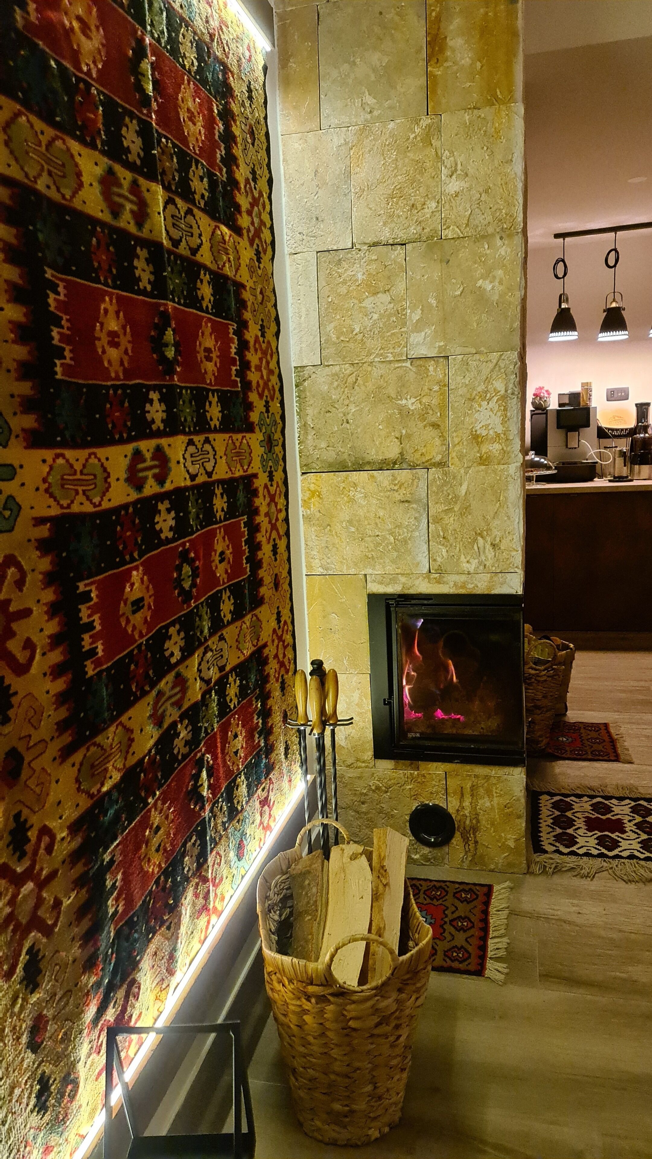 Una habitación acogedora con chimenea de piedra, una cesta tejida y un papel tapiz estampado.