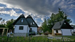 A traditional building with a steep roof and a small window, surrounded by a fenced garden area. - Plitvice Holiday Lodge (Plitvicka Jezera)