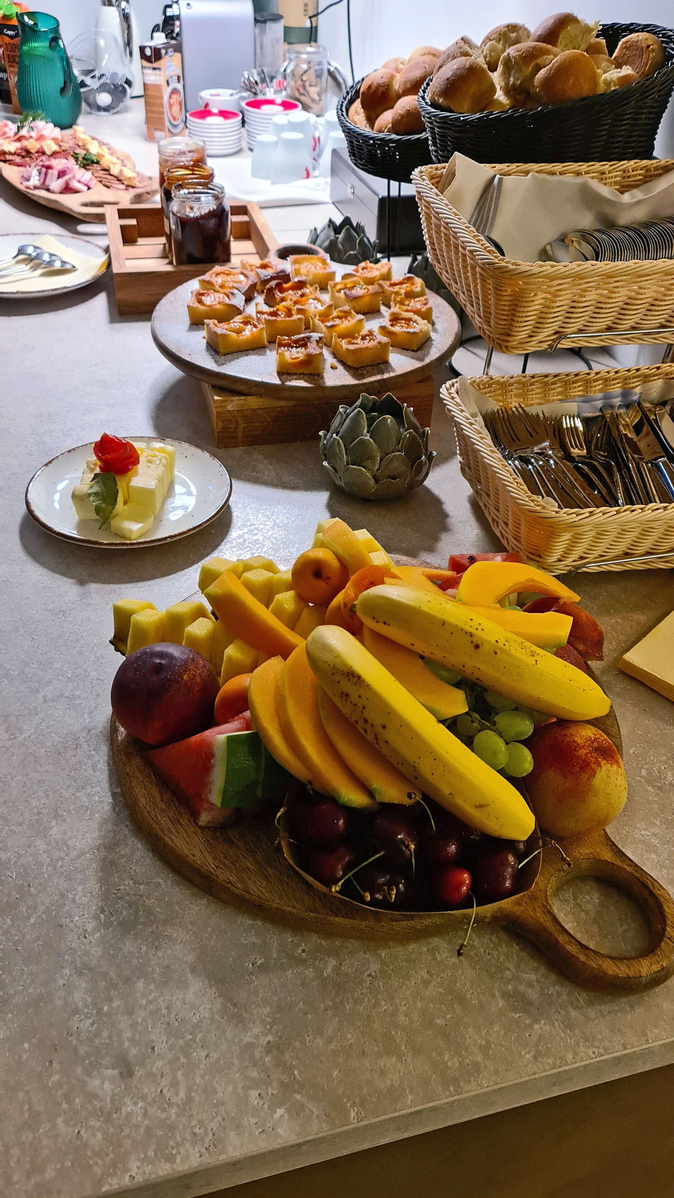 A buffet table with various food items including fruits, pastries, and desserts.