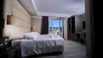 A hotel room with a bed, a desk, a chair, a TV, and a view of the outdoors.