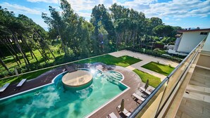 A swimming pool with a circular hot tub, surrounded by a deck with lounge chairs and a grassy area. - PARK HOTEL LE DUNE DI GIOVINO (Catanzaro)