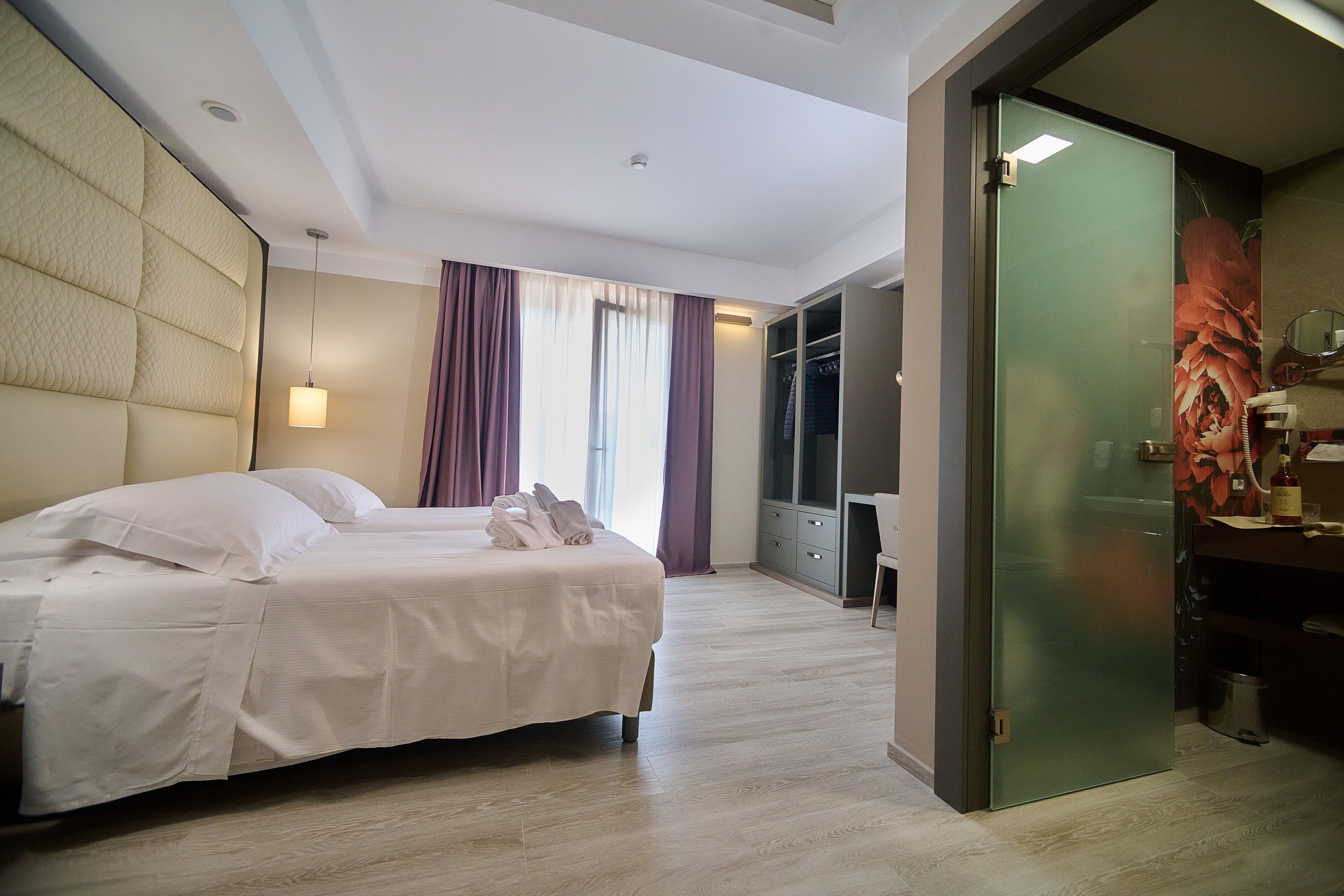 A hotel room with a bed, a desk, a wardrobe, and a bathroom.