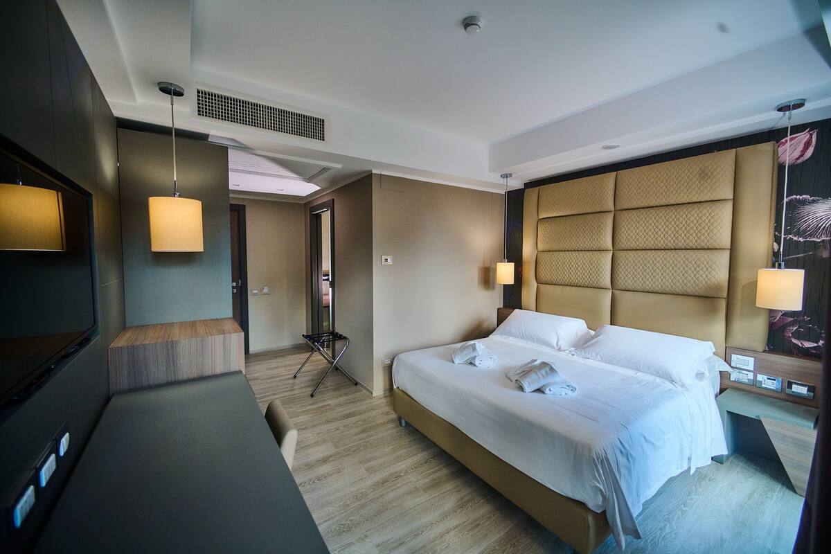 A modern hotel room with a large bed, a flat-screen TV, and a desk.