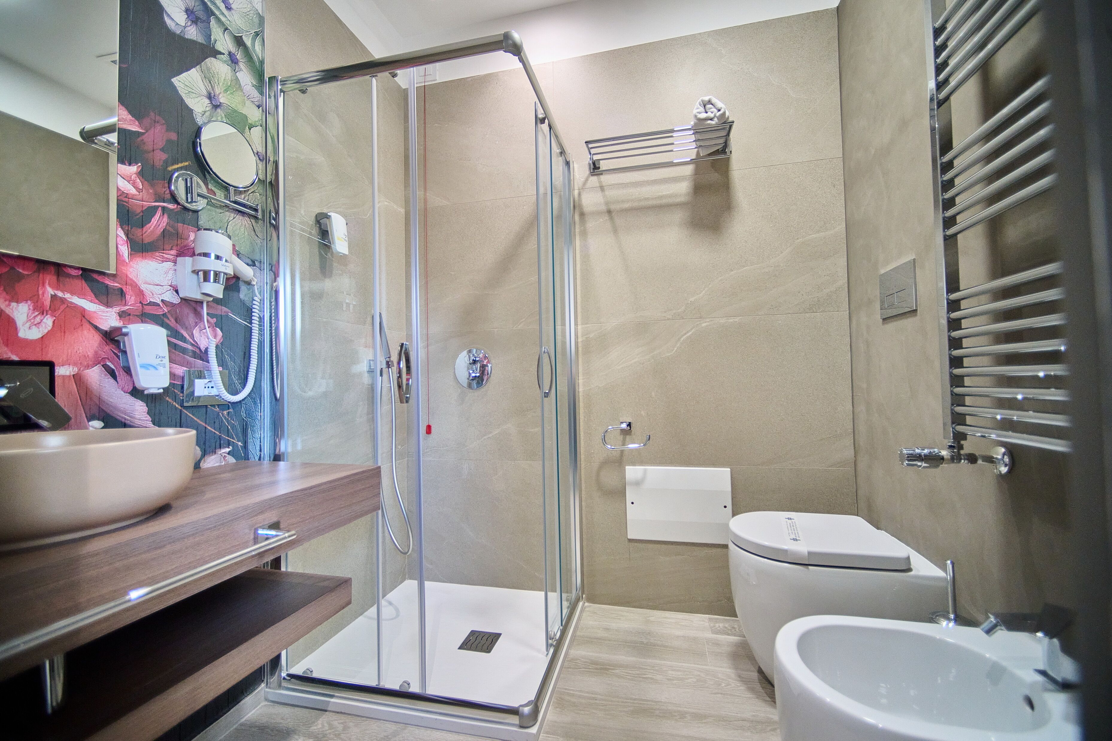 A modern bathroom with a glass shower enclosure, a wooden vanity with a bowl sink, a white toilet, and a bidet.