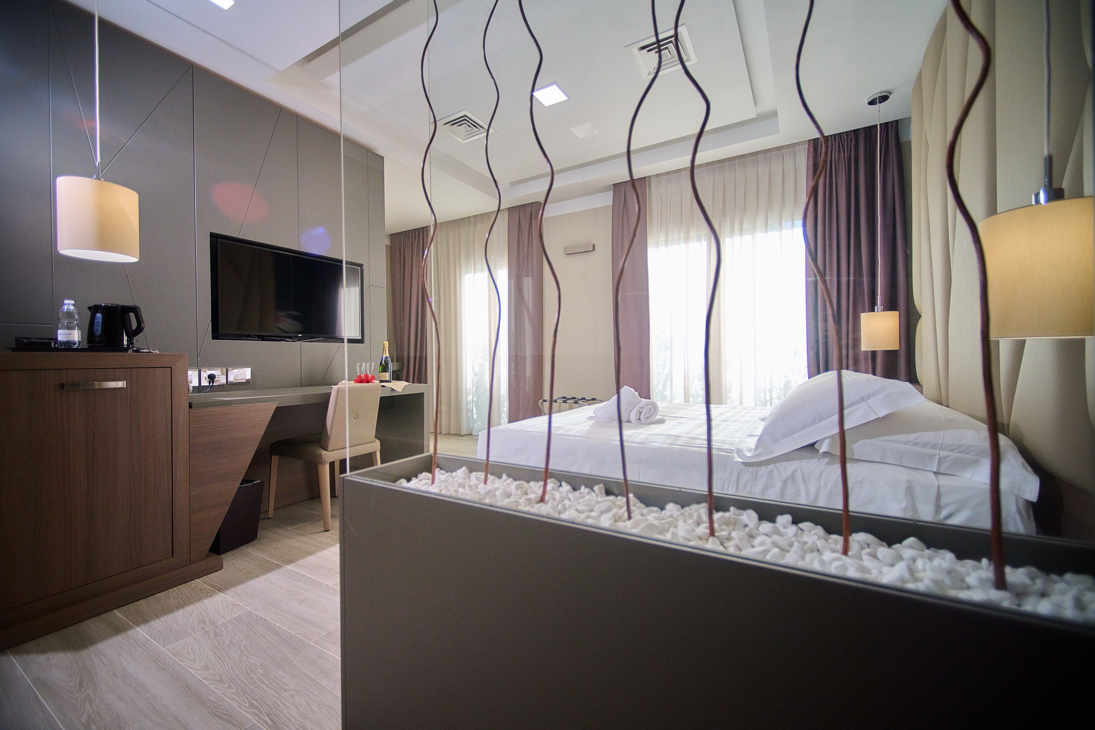 Ein modernes Hotelzimmer mit Bett, Schreibtisch, Fernseher und Minibar.
