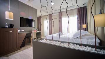 Ein modernes Hotelzimmer mit Bett, Schreibtisch, Fernseher und Minibar.