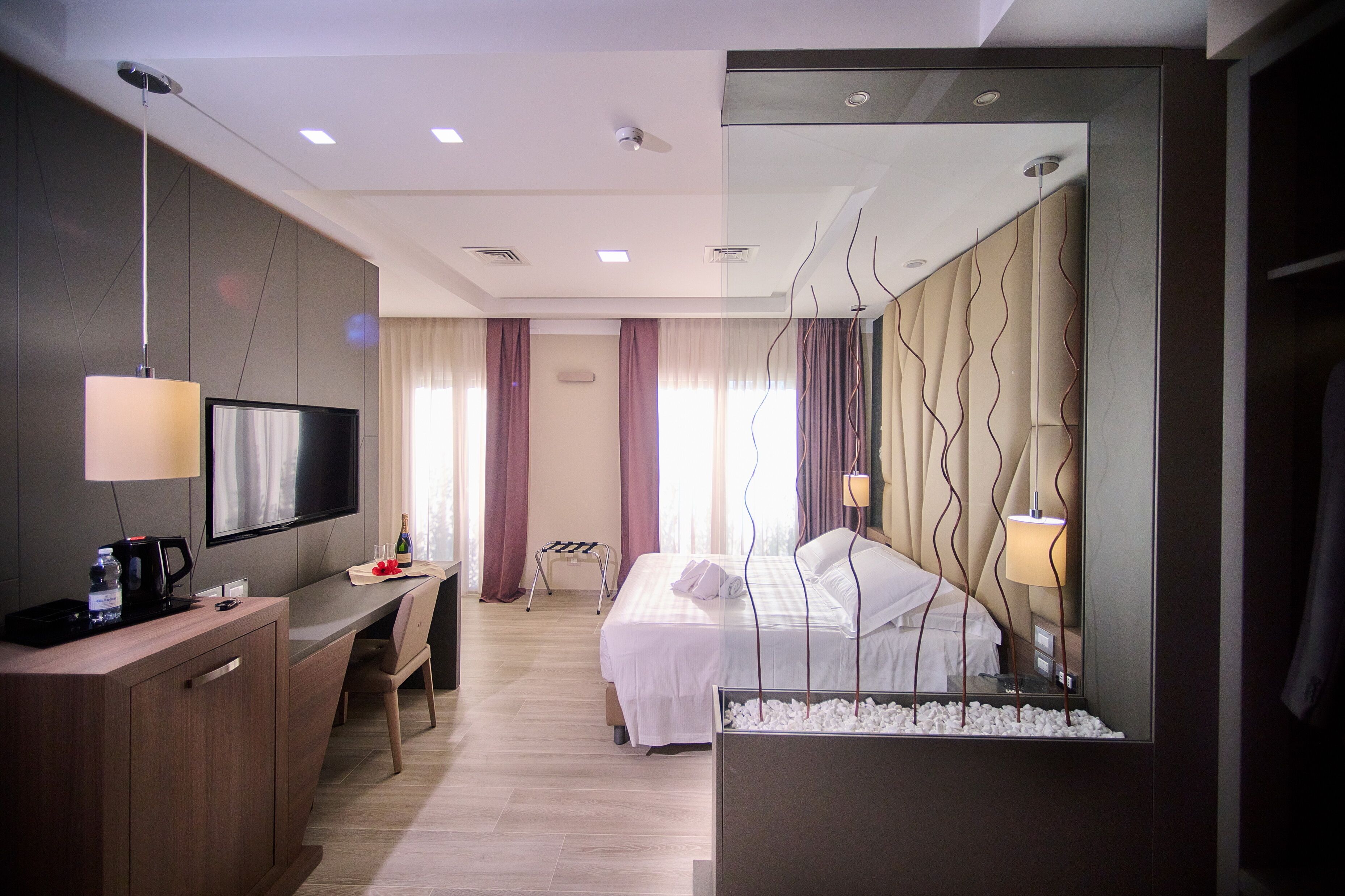 A hotel room with a bed, bedside table, TV, and a desk with a chair.