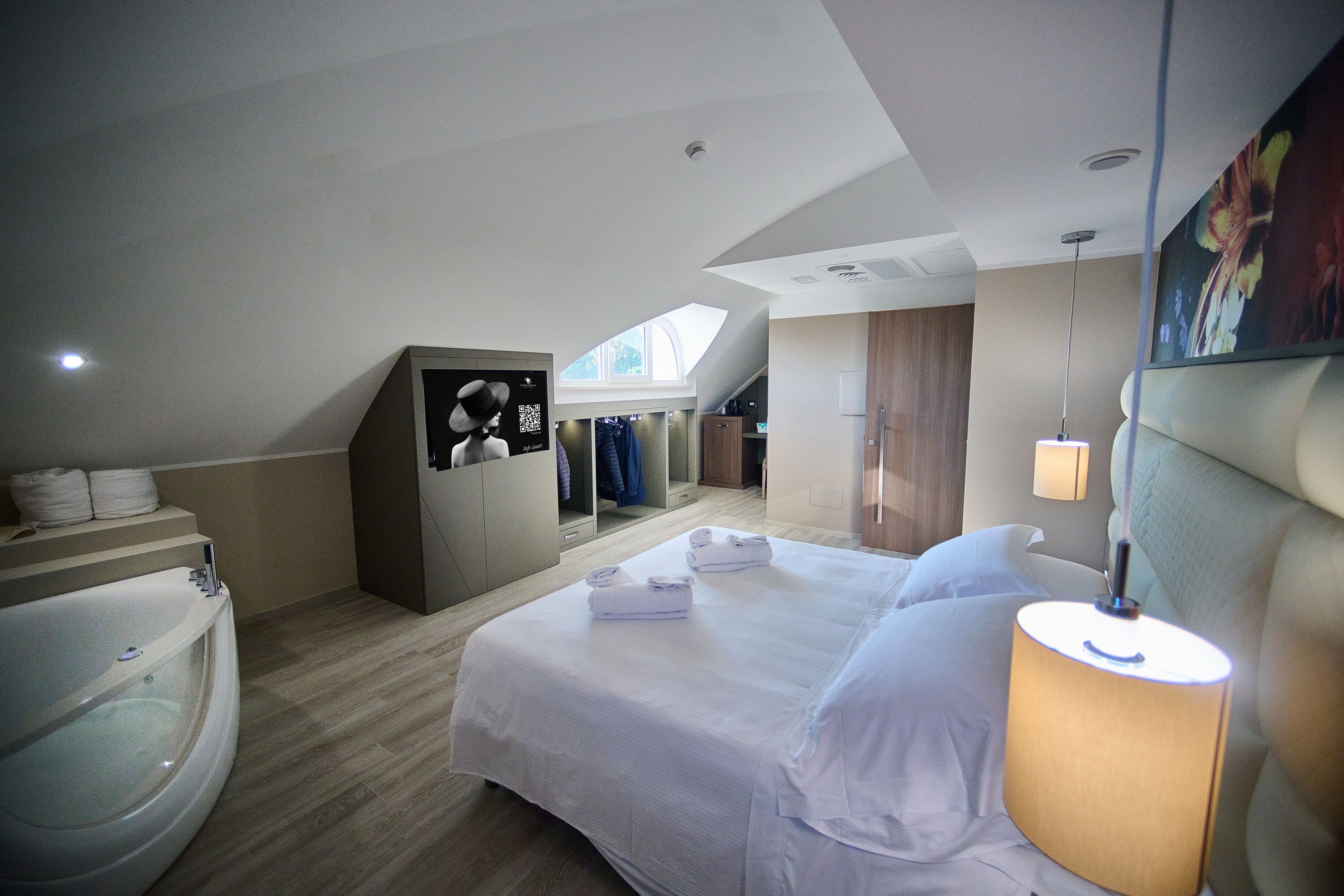 Et moderne hotelværelse med en stor seng, et badekar og et skydetagvindue.