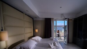 A hotel room with a large bed, a bedside table, a lamp, and a view of the outside balcony. - PARK HOTEL LE DUNE DI GIOVINO (Catanzaro)