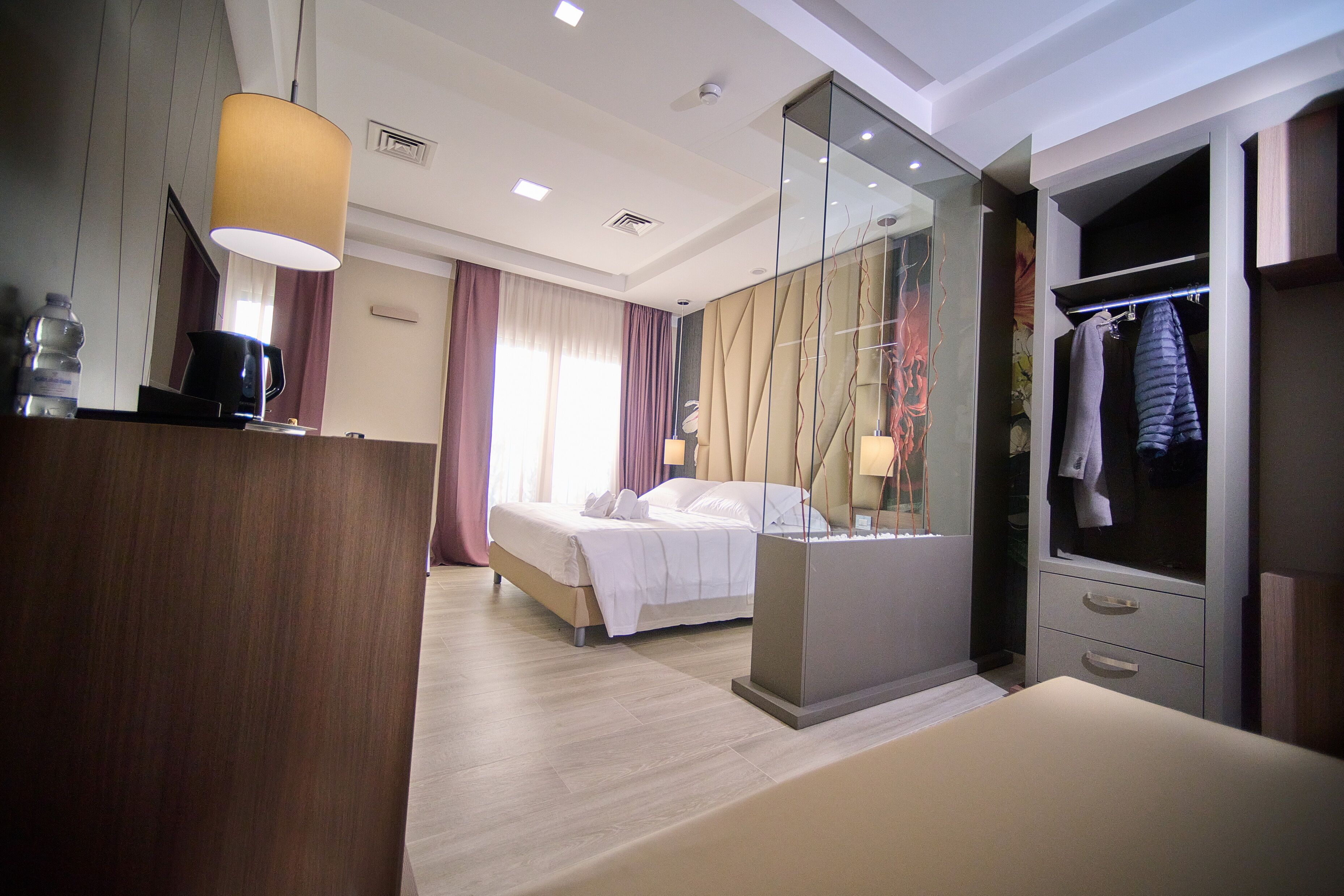 Une chambre d’hôtel comprenant un lit, un bureau avec une lampe, une armoire et un miroir.