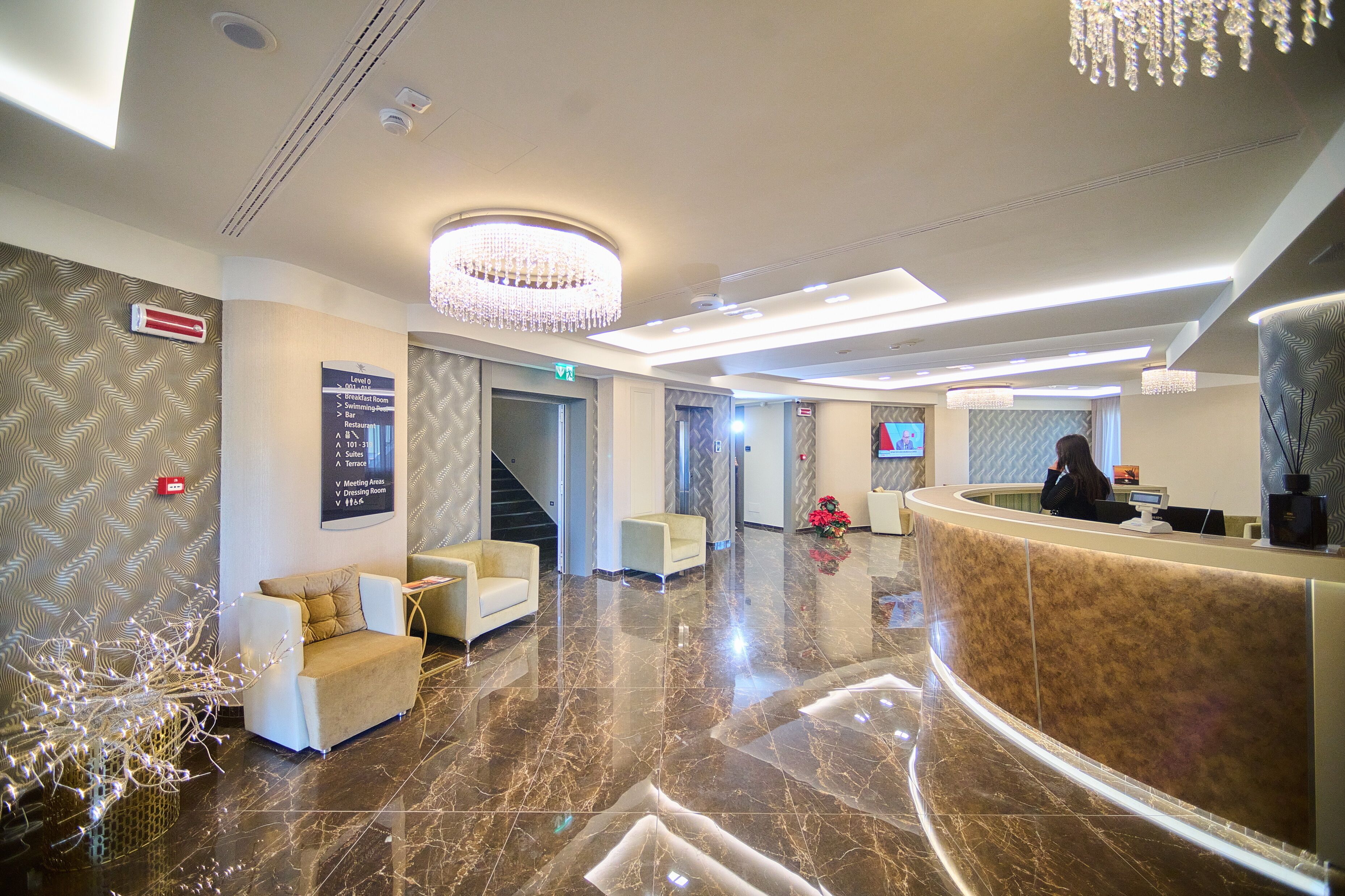 A hotel lobby with a reception desk, seating area, and a staircase.