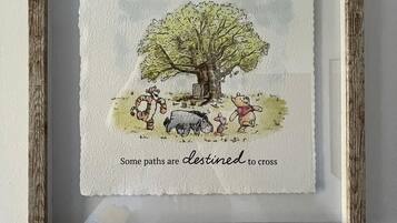 A framed artwork with a tree and animals, and the text 'some paths are destined to cross.'