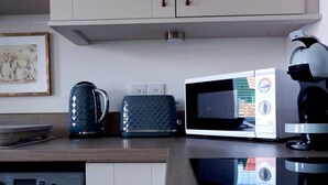 Una cocina equipada con lavadora, microondas, tostadora y hervidor.