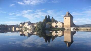 A historic town with a prominent tower and buildings reflected in a calm body of water.