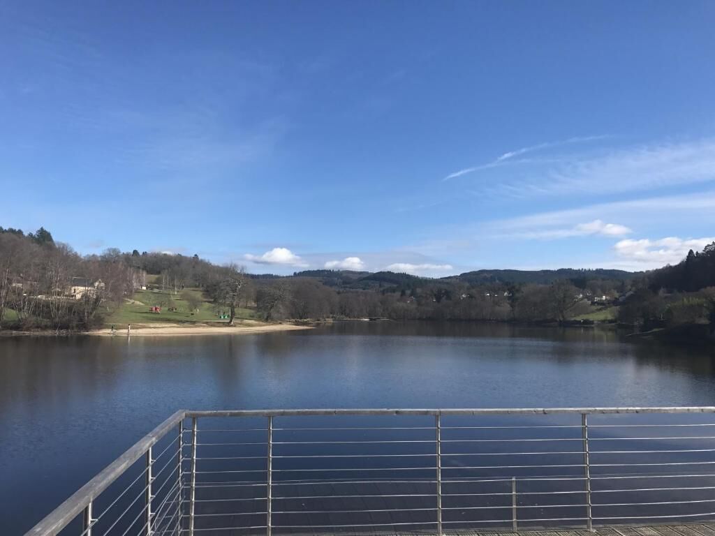 Un lago tranquilo con un muelle de madera al frente.
