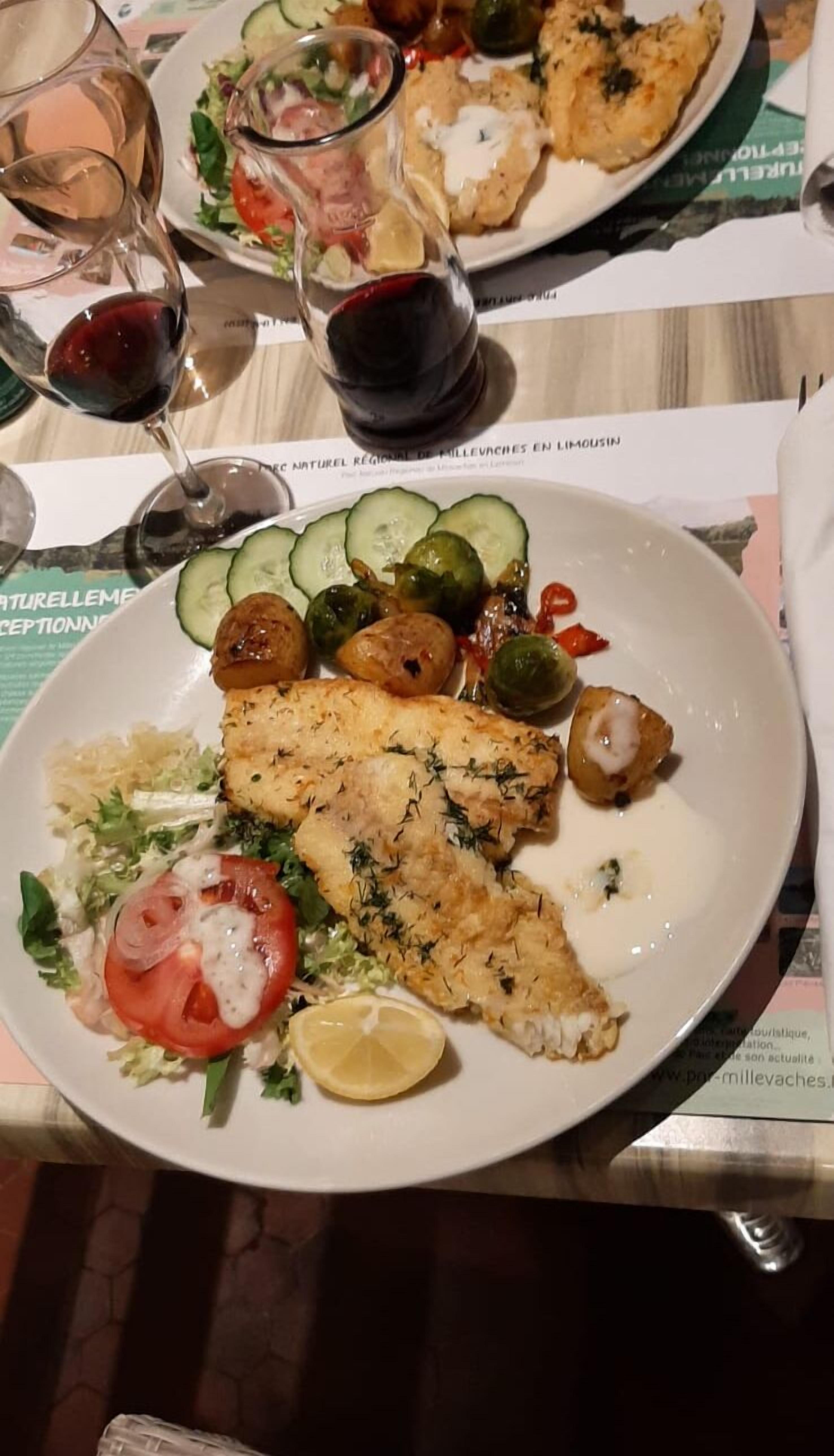 Un plato de comida con un filete de pescado, verduras y una rodaja de limón.