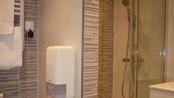A modern bathroom with a glass-enclosed shower, a hand dryer, and a toilet.