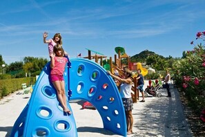 A playground with a blue slide and a wooden play structure.