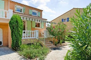 A two-story building with a garden entrance, a staircase, and a small balcony.