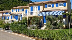 A row of Mediterranean-style buildings with balconies, blue shutters, and a striped awning. - Terraced House in Vidauban with Pool (Vidauban)