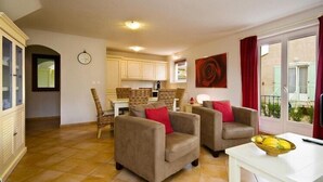 A living room with two armchairs, a dining table, and a kitchen in the background. - Terraced House in Vidauban with Pool (Vidauban)