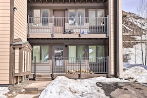 Stunning two-story home with a balcony and brick exterior, set amidst a serene hillside.