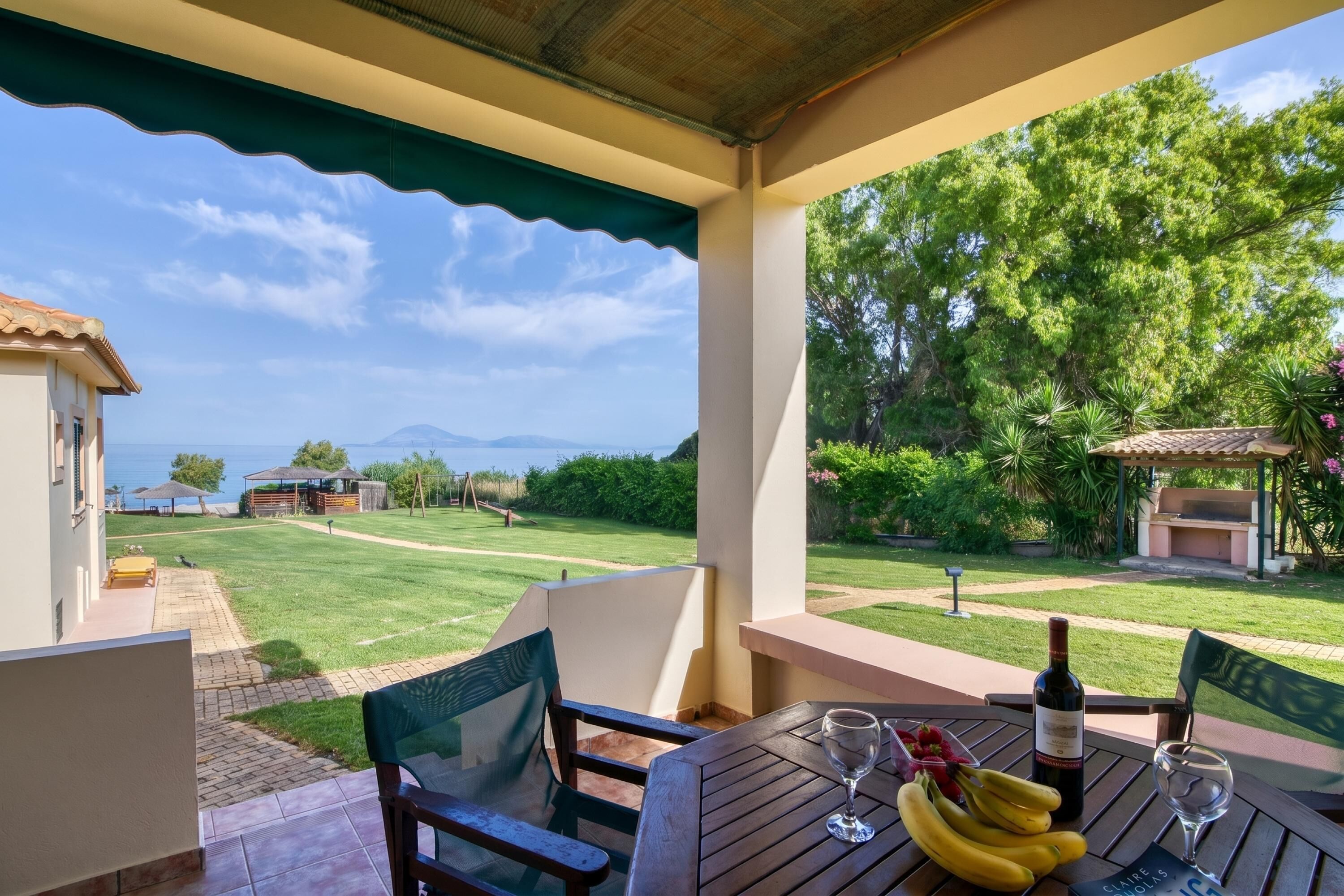 A patio with a table set for dining, a bottle of wine, and a glass.