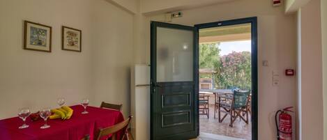 Comedor con una mesa dispuesta para dos personas, un refrigerador y una puerta que da a un patio exterior.