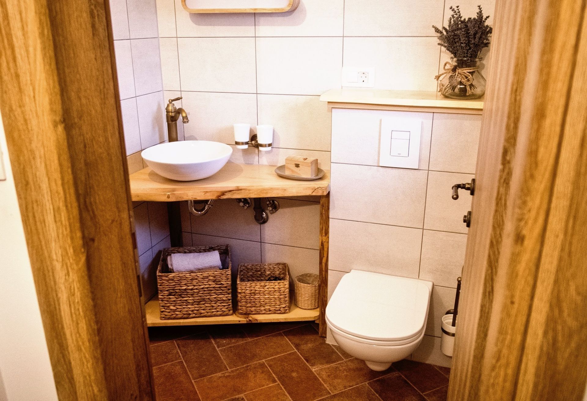 Ein kleines Badezimmer mit einem Holzbadezimmer-Schrank, einem weißen Waschbecken, einer Toilette und Körben aus Weidengeflecht.