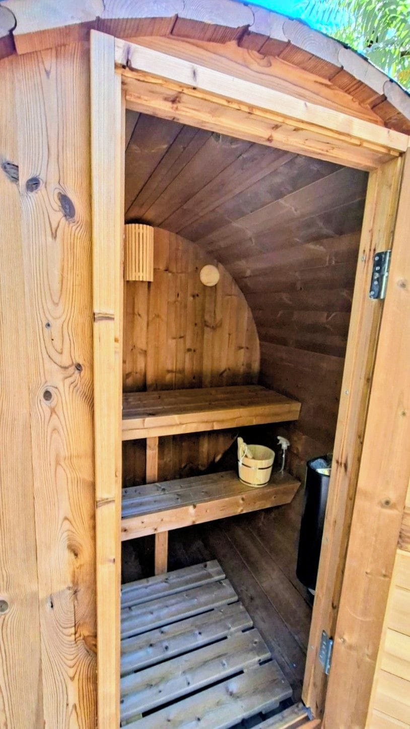 Un sauna en bois avec un banc, des étagères et un seau.