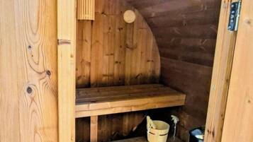 Un sauna en bois avec un banc, des étagères et un seau.