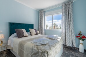 A hotel room with a bed, a window with curtains, a vase with flowers, and a nightstand with a lamp. - Villa 'Galicia' with Mountain View, Private Pool and Wi-Fi (Calpe)
