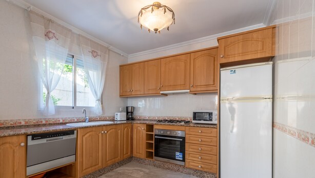 A kitchen with wooden cabinets, a white refrigerator, a microwave, an oven, and a dishwasher.