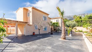 A building with a tiled roof, a tree in the courtyard, and a mountain in the background. - Villa 'Galicia' with Mountain View, Private Pool and Wi-Fi (Calpe)